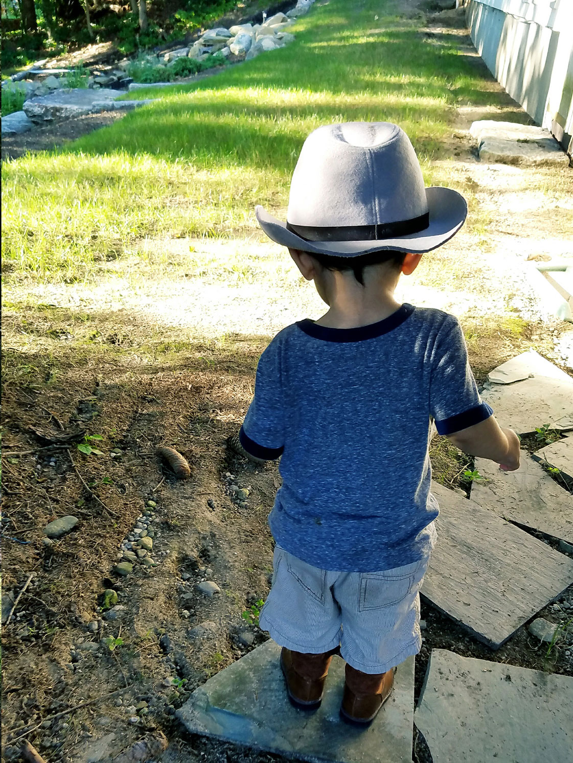 Little one in hat inspecting dirt.